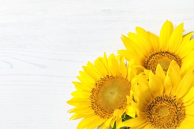 Photo of Yellow sunflowers on wooden background, top view