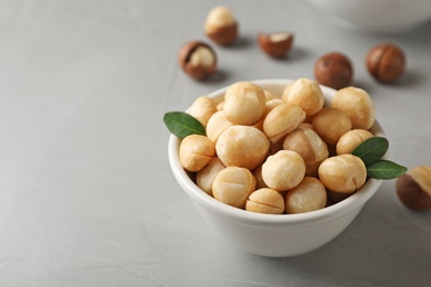 Photo of Bowl with shelled organic Macadamia nuts and space for text on grey background