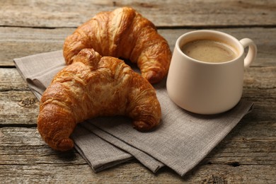 Delicious fresh croissants and cup of coffee on table
