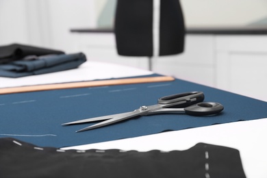 Photo of Fabric and scissors on table in tailor workshop
