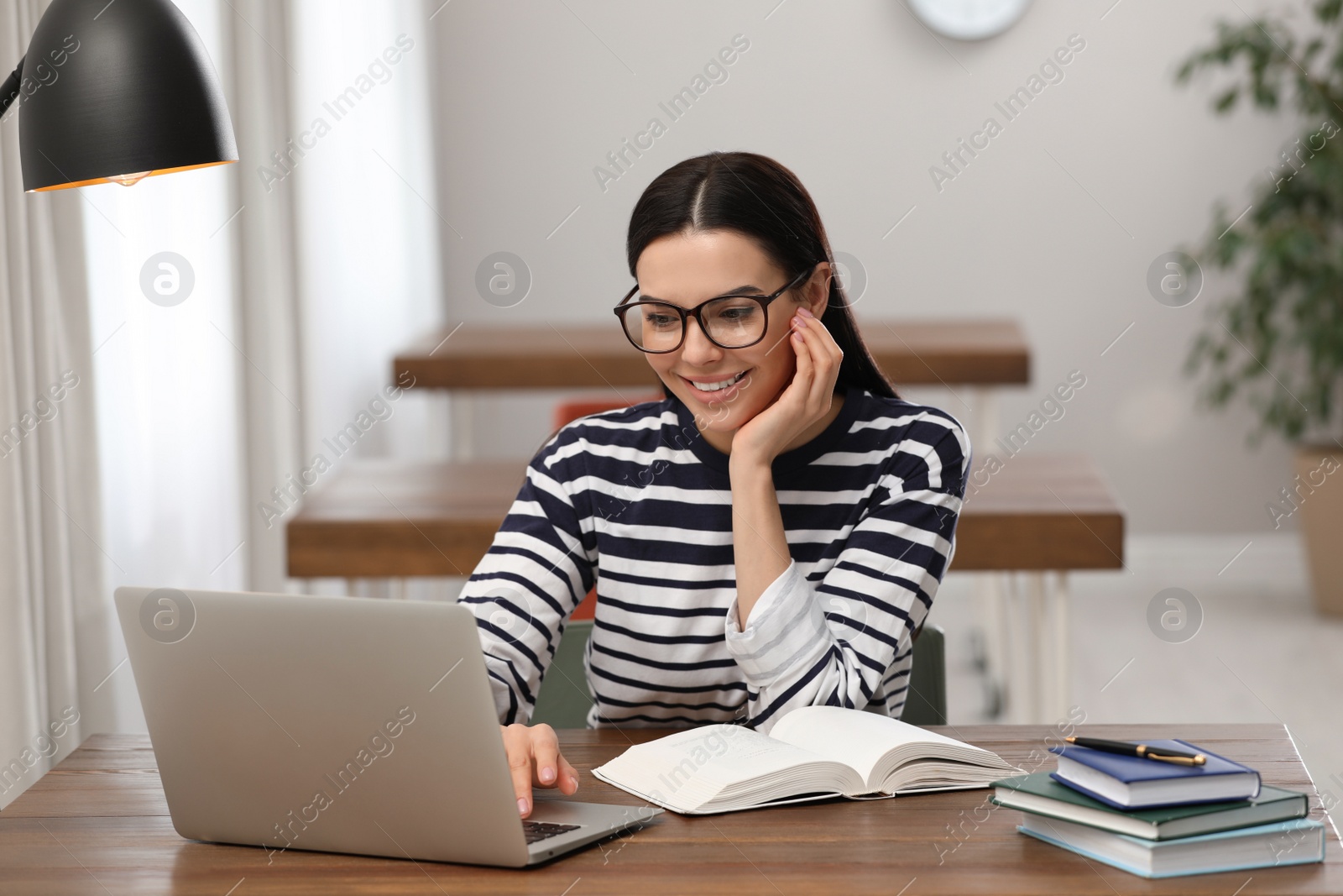 Photo of Young woman with laptop studying at table in library