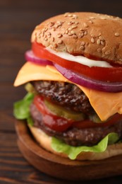 Photo of Tasty cheeseburger with patties on wooden table, closeup