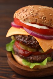 Tasty cheeseburger with patties on wooden table, closeup