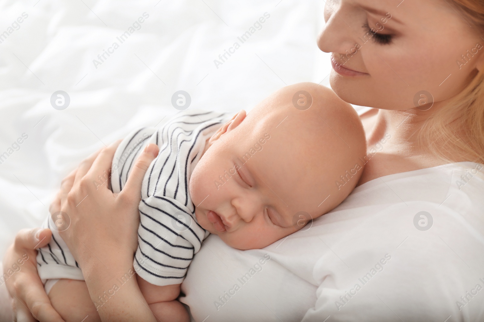 Photo of Mother with her sleeping baby om light background