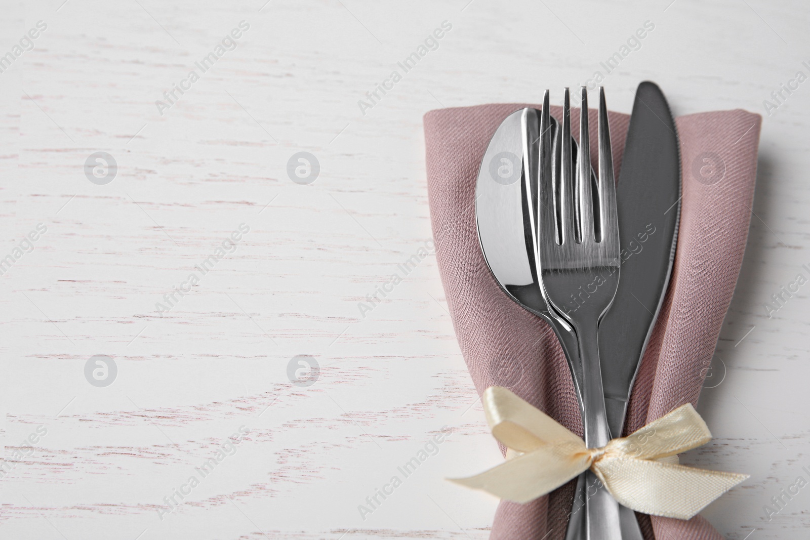 Photo of Cutlery set for festive table on white wooden background. Space for text