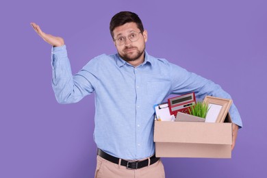 Unemployed man with box of personal office belongings on purple background