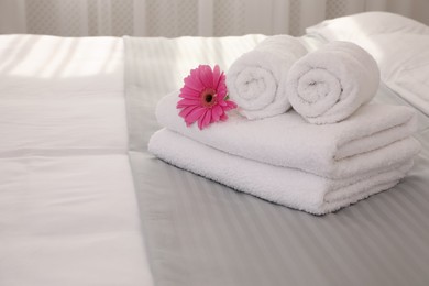 Photo of Fresh white towels with flower on bed indoors, space for text