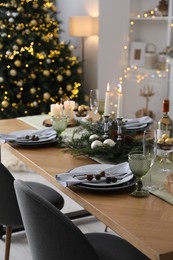 Christmas table setting with festive decor and dishware in room