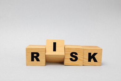 Photo of Wooden cubes with word Risk on light grey background