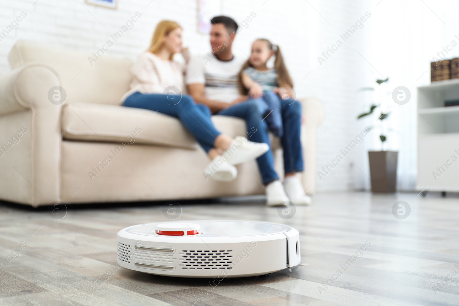 Photo of Family resting while robotic vacuum cleaner doing its work at home