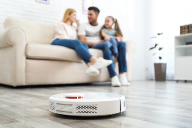 Photo of Family resting while robotic vacuum cleaner doing its work at home
