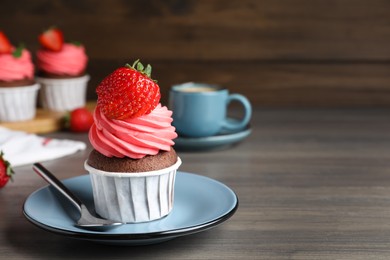 Photo of Sweet cupcake with fresh strawberry on wooden table. Space for text