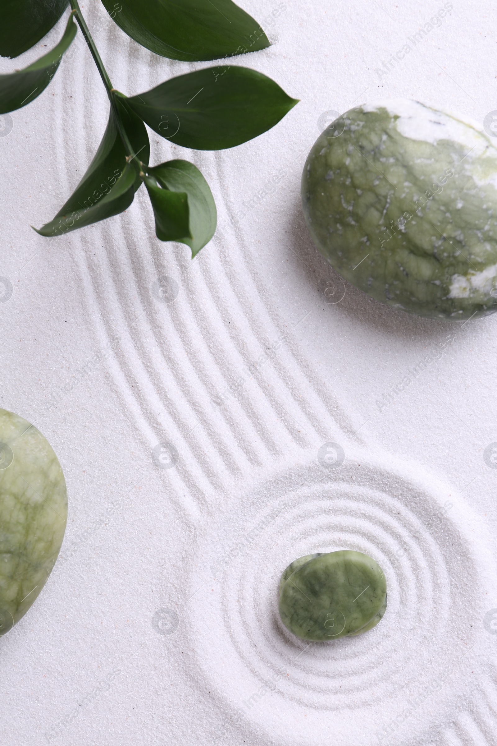 Photo of Zen concept. Stones, leaves and pattern on white sand, flat lay