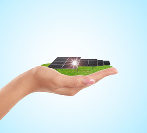 Woman demonstrating solar panel on light blue background, closeup. Alternative energy source 