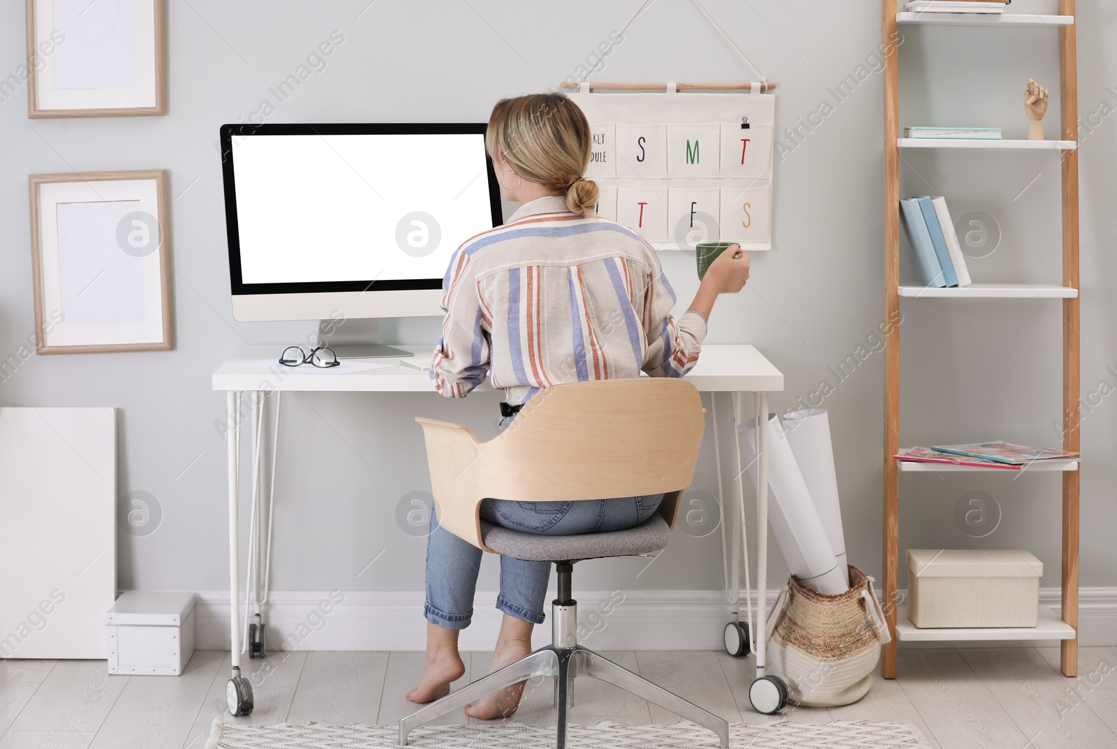 Photo of Young woman working on computer at table in room