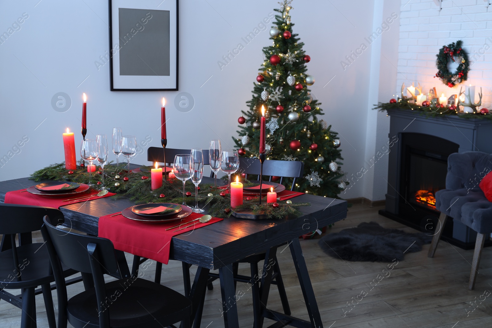 Photo of Elegant Christmas table setting with dishware and burning candles in festively decorated room