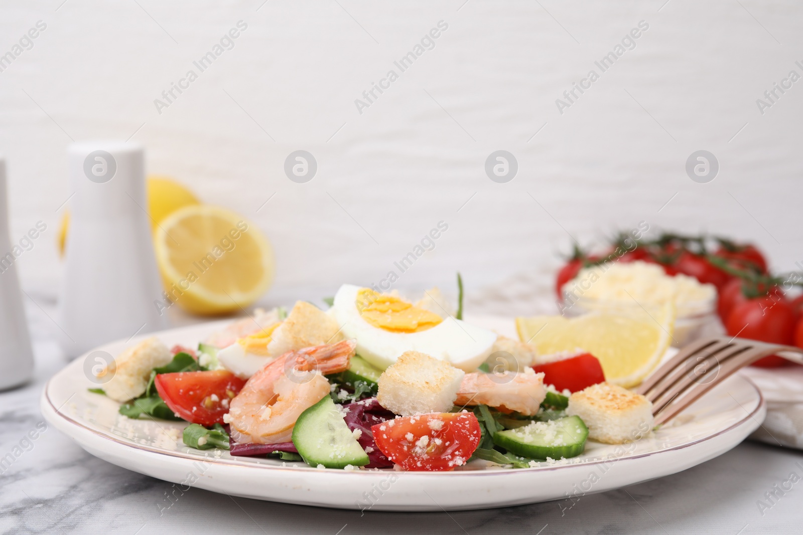 Photo of Delicious Caesar salad with shrimps on white marble table, closeup