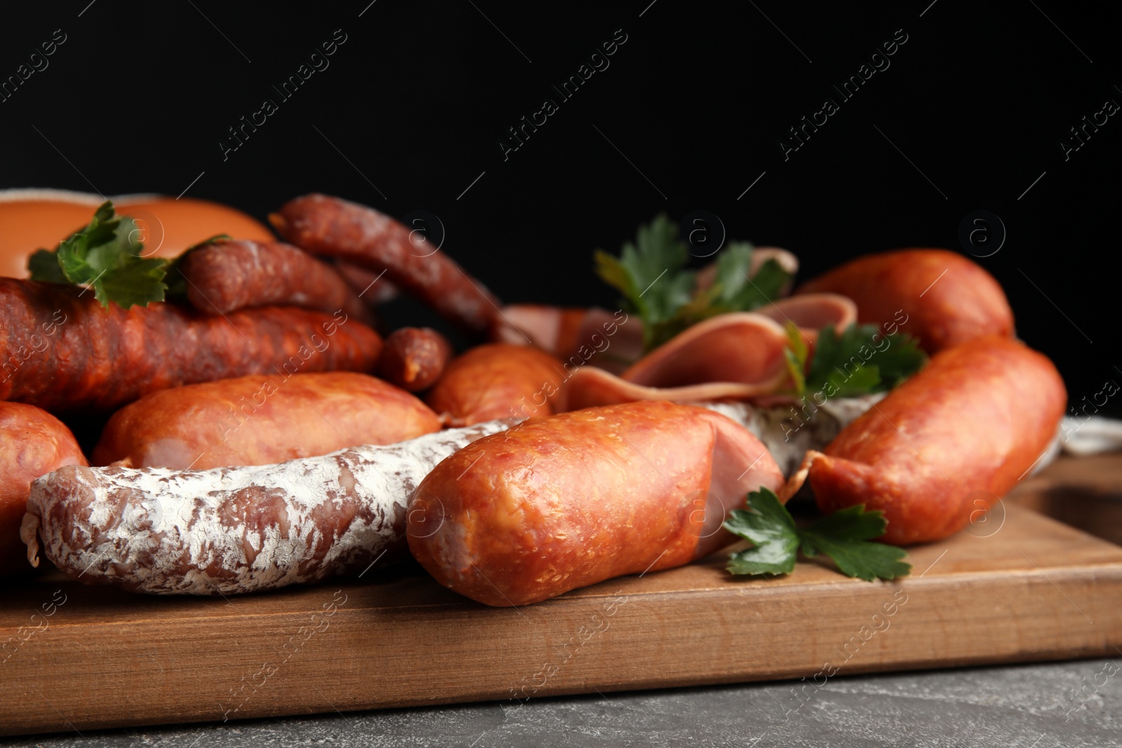 Photo of Different tasty sausages on wooden board, closeup