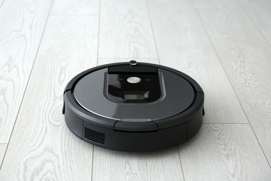 Modern robotic vacuum cleaner on wooden floor