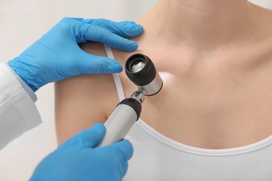 Photo of Dermatologist with dermatoscope examining patient in clinic, closeup