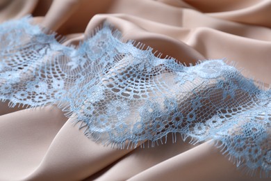 Beautiful light blue lace on beige fabric, closeup