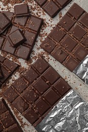 Pieces and shavings of tasty chocolate bars on light grey table, flat lay