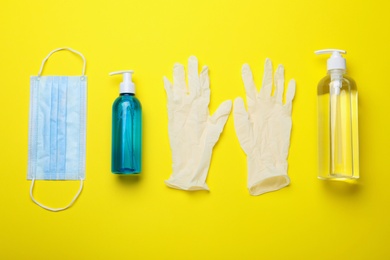 Photo of Medical gloves, mask and hand sanitizers on yellow background, flat lay