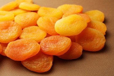 Many tasty dried apricots on pale brown background, closeup. Healthy snack