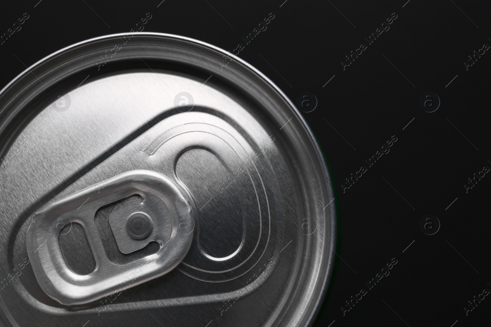 Photo of Energy drink in can on black background, top view. Space for text