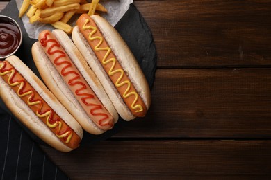 Photo of Delicious hot dogs with sauces on wooden table, top view. Space for text