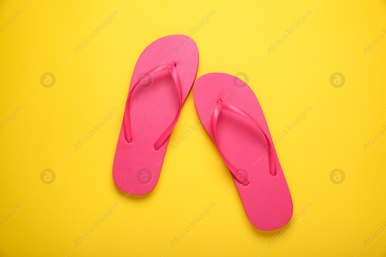 Photo of Stylish pink flip flops on yellow background, top view