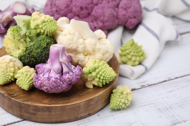 Photo of Various cauliflower cabbages on white wooden table, closeup. Space for text