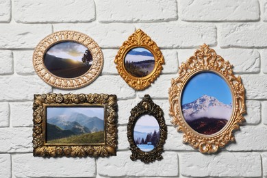 Photo of Vintage frames with photos of beautiful landscapes hanging on white brick wall