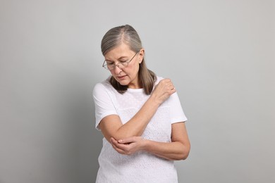 Photo of Arthritis symptoms. Woman suffering from pain in elbow on gray background