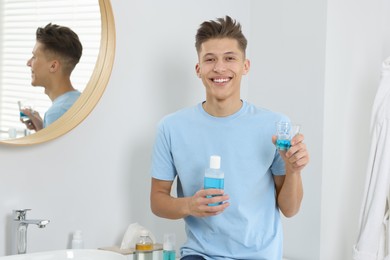 Photo of Young man with mouthwash in bathroom. Oral hygiene