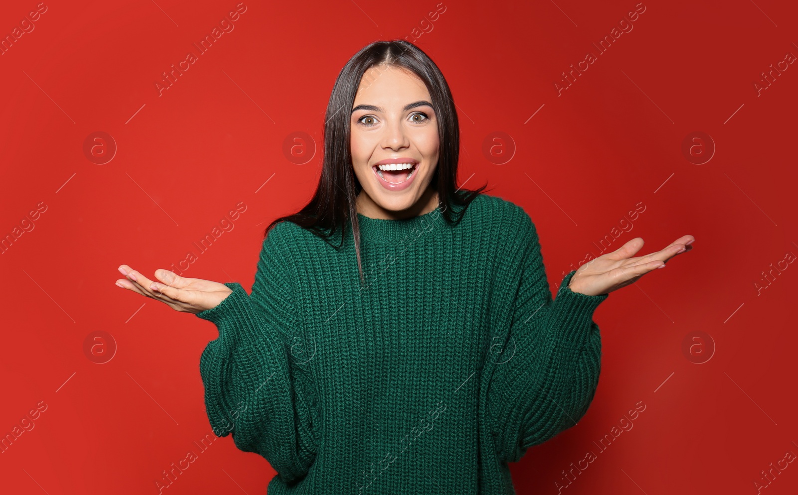 Image of Excited woman wearing warm sweater on red background