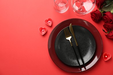 Place setting with heart shaped candles and bouquet of roses for romantic dinner on red table, flat lay. Space for text