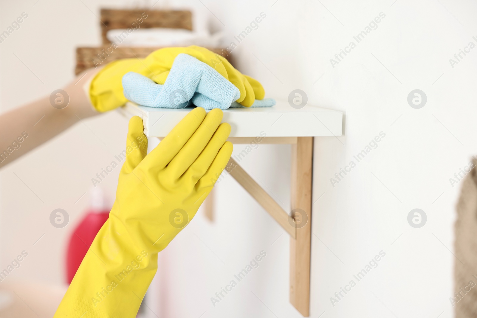 Photo of Woman cleaning shelf with rag at home, closeup