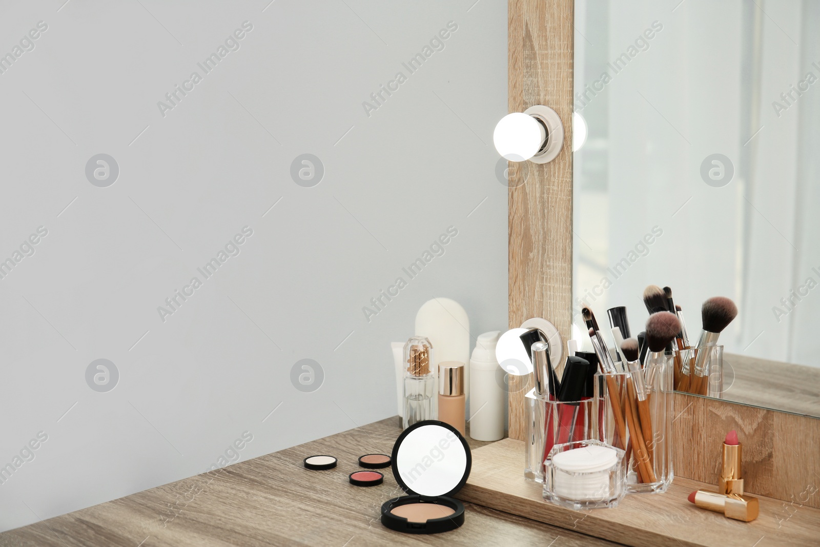 Photo of Makeup cosmetic products with tools in organizer on dressing table. Space for text