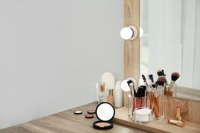 Makeup cosmetic products with tools in organizer on dressing table. Space for text