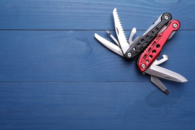 Photo of Modern compact portable multitool on blue wooden table, top view. Space for text