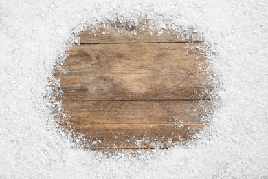 Frame made of snow on wooden background, top view with space for text. Christmas season