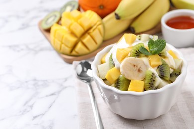 Photo of Delicious fruit salad on white marble table, space for text