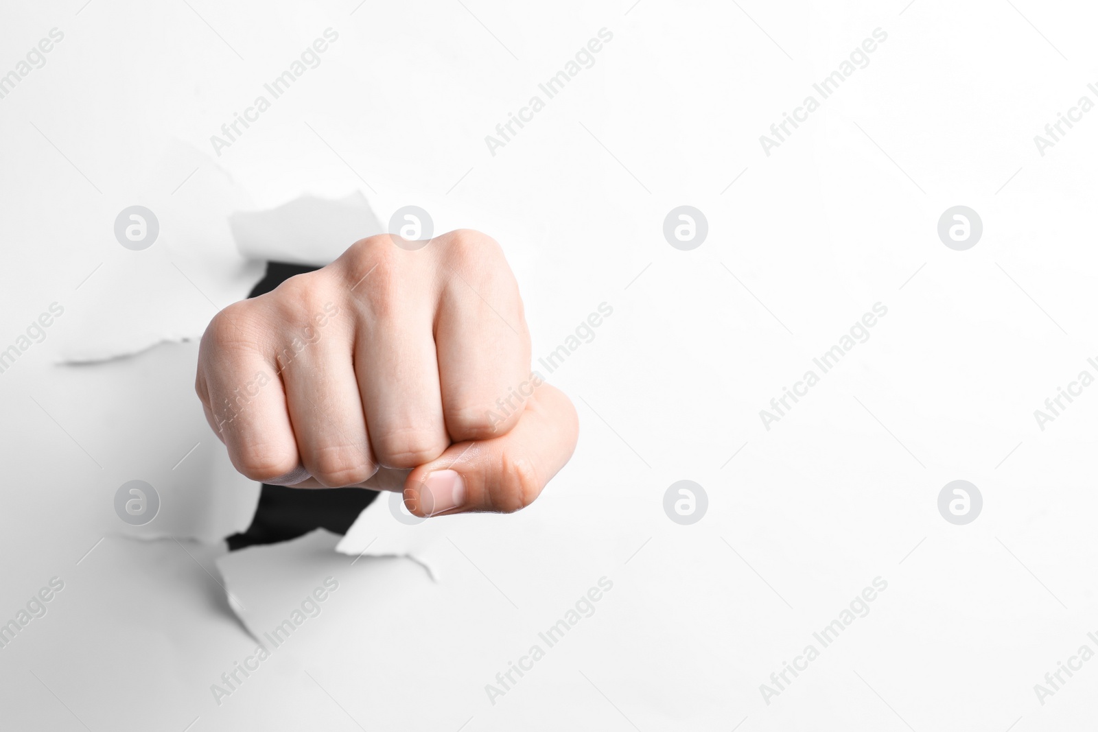 Photo of Man breaking through white paper with fist, closeup. Space for text