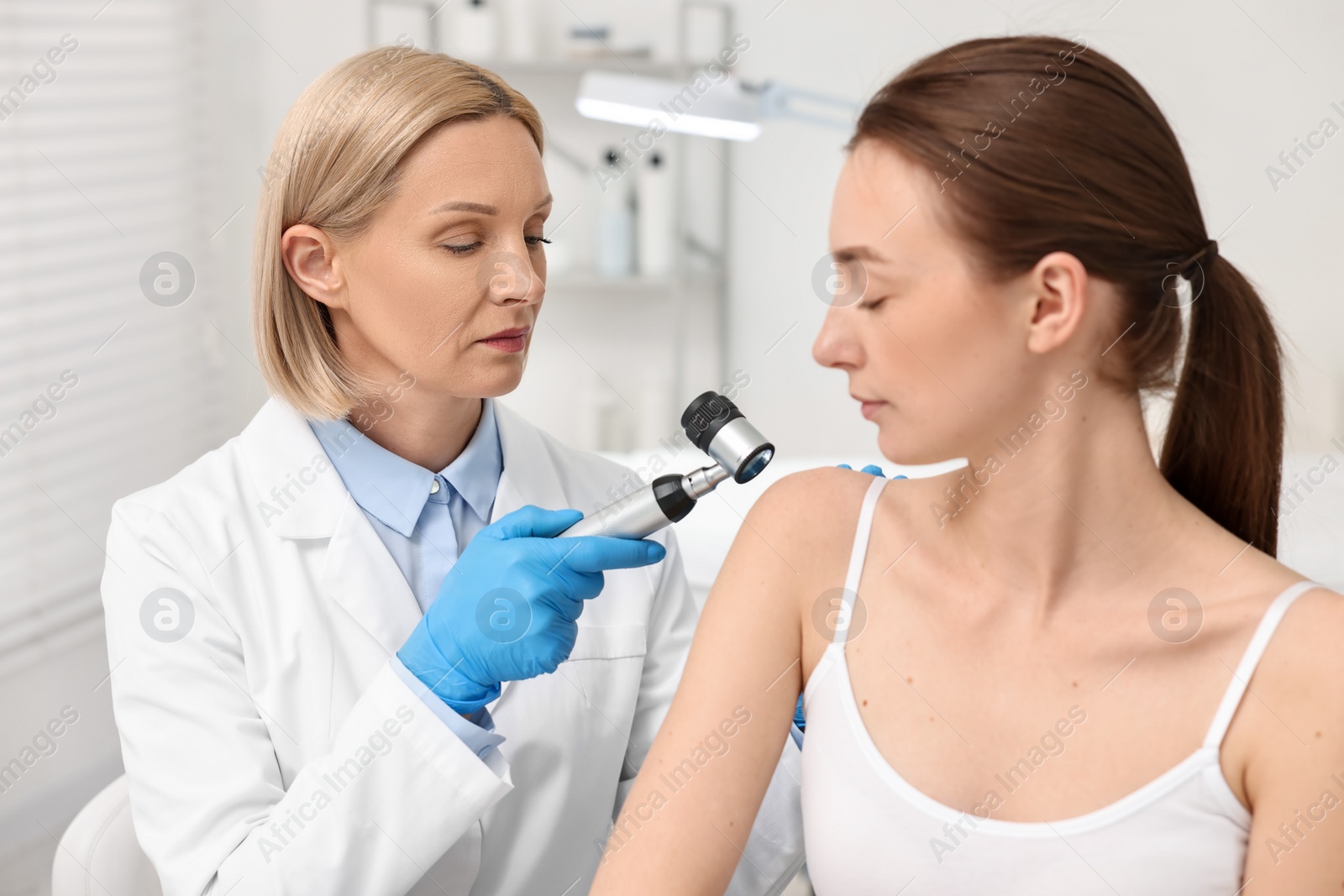 Photo of Dermatologist with dermatoscope examining patient in clinic