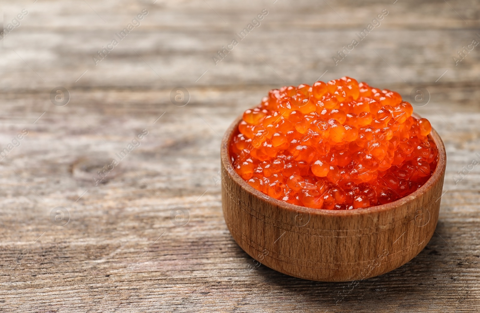 Photo of Bowl with delicious red caviar on table