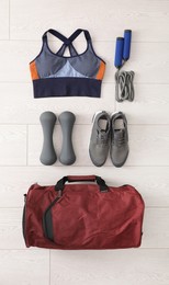 Photo of Red bag and sports accessories on floor, flat lay