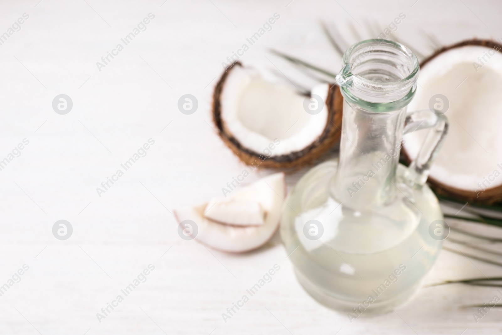 Photo of Coconut oil on white wooden table, closeup. Space for text