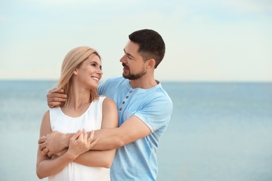 Photo of Happy romantic couple spending time together on beach, space for text