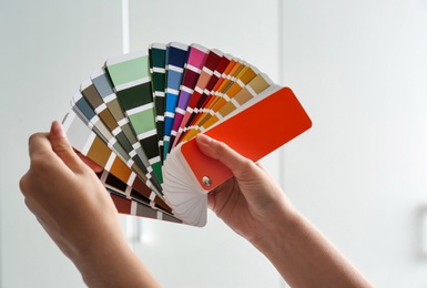 Photo of Female interior designer with color palette samples indoors, closeup